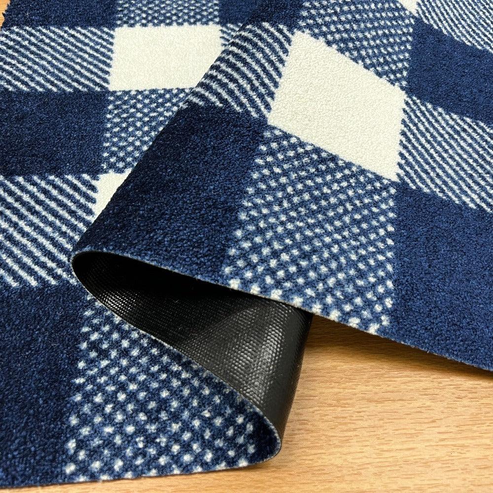 Close-up of a blue and white checkered rug with a black border on a wooden floor.