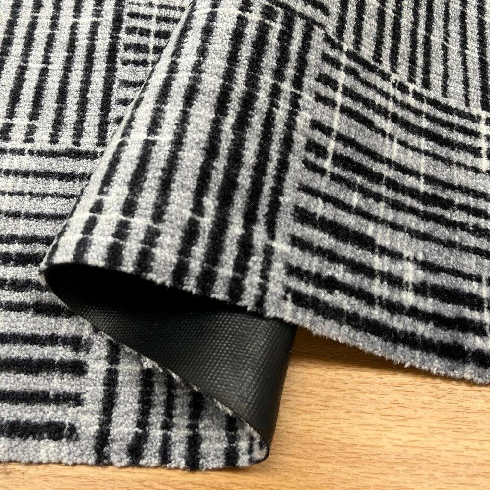 Close-up of a textured black and gray rug on a wooden floor
