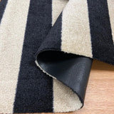 Close-up of Farmhouse striped Floor Mat with black and Sand colors on a wooden floor.