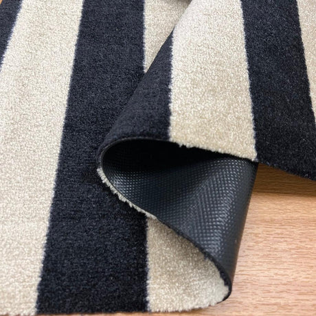 Close-up of Farmhouse striped Floor Mat with black and Sand colors on a wooden floor.