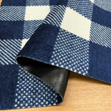 Close-up of a blue and white checkered rug with a black border on a wooden floor.